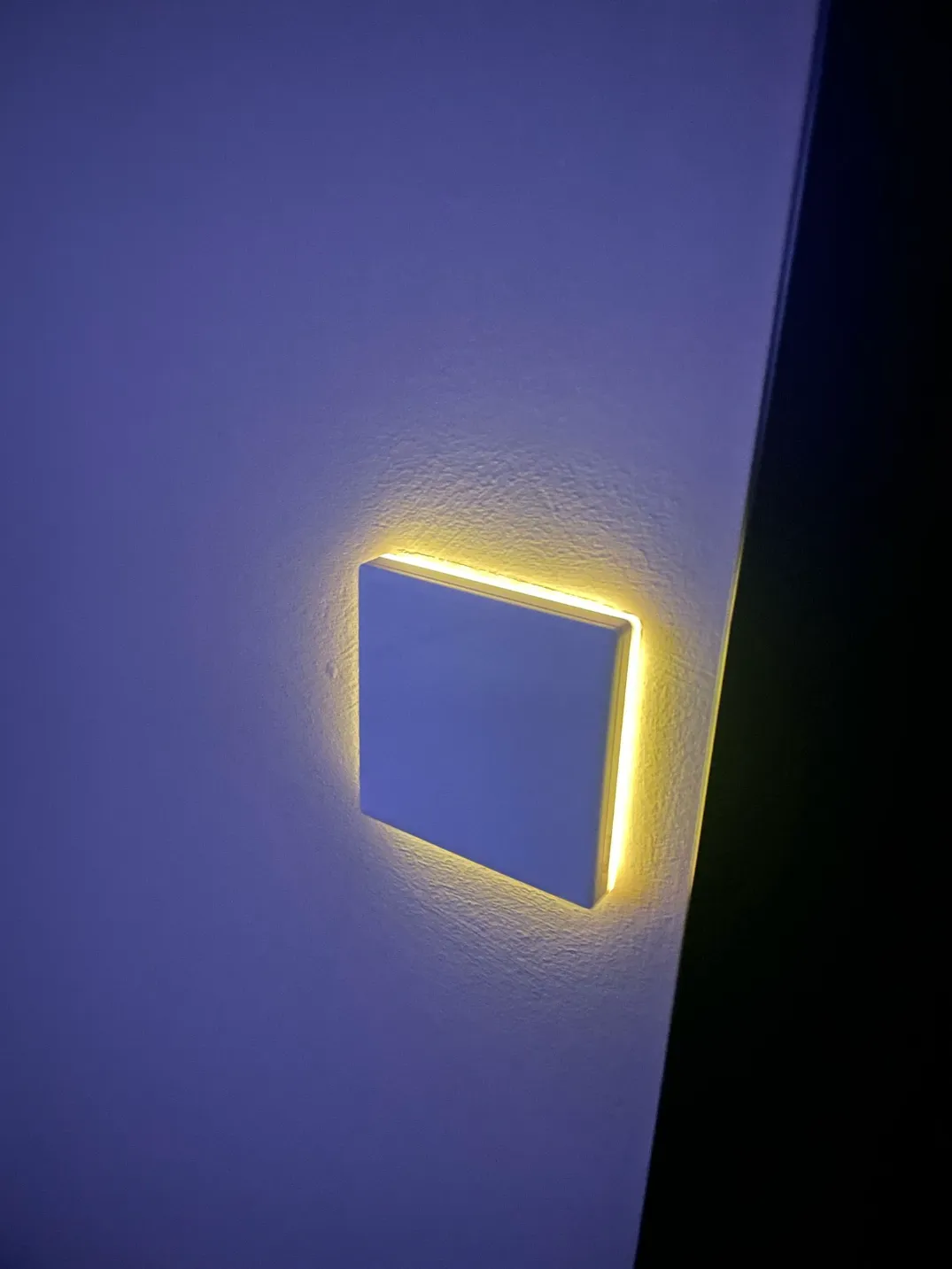 Smart wall light switch with soft ambient LED backlight used for night-time navigation in a smart home.